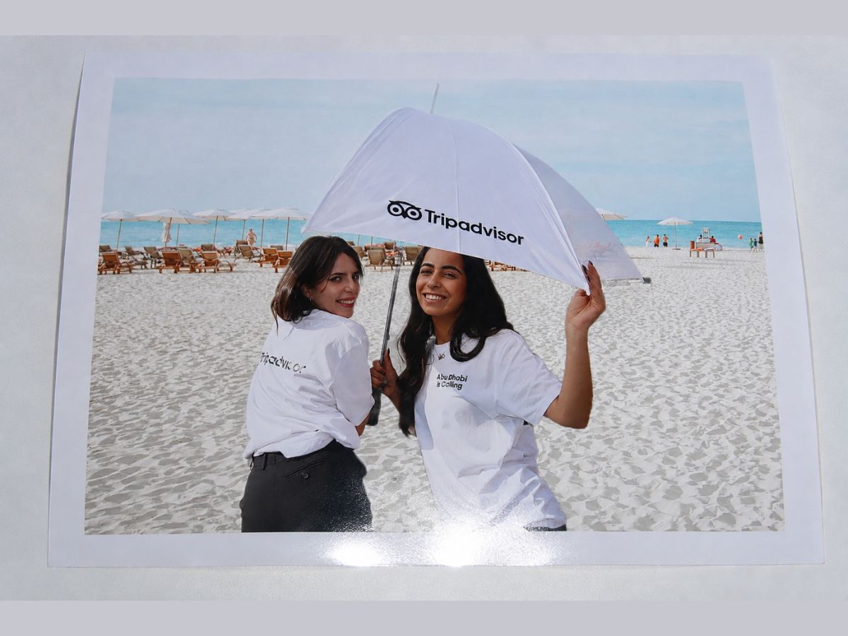 Branded Tripadvisor print showing two guests on an Abu Dhabi beach with a Tripadvisor umbrella