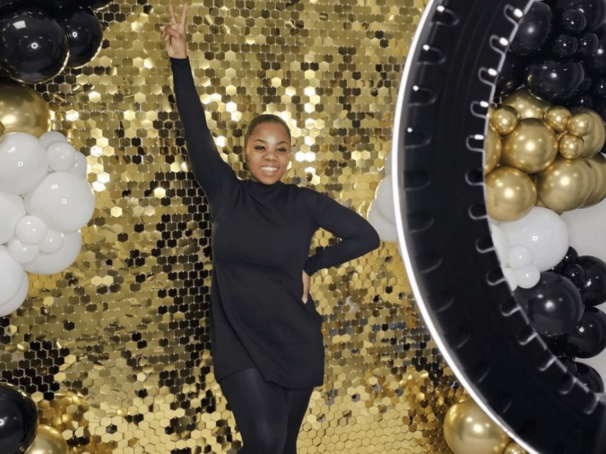 Guest photographed against a gold sequin shimmer wall with a studio ring light at a London event