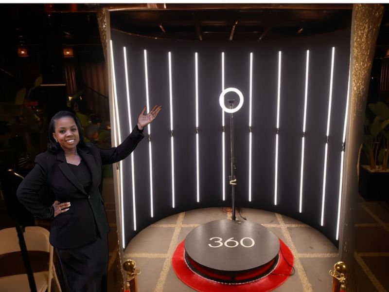 An event host presenting an illuminated 360 video booth at a corporate evening event