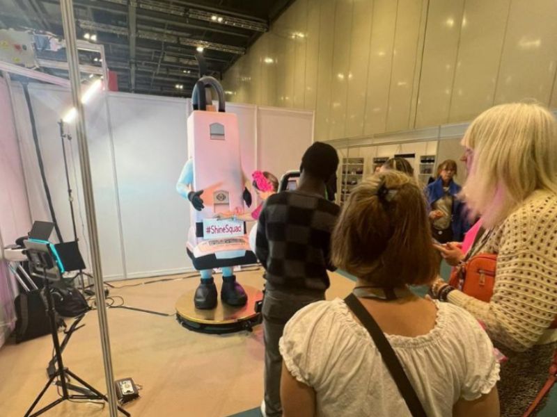Visitors gathering around a 360 video booth at a busy exhibition stand