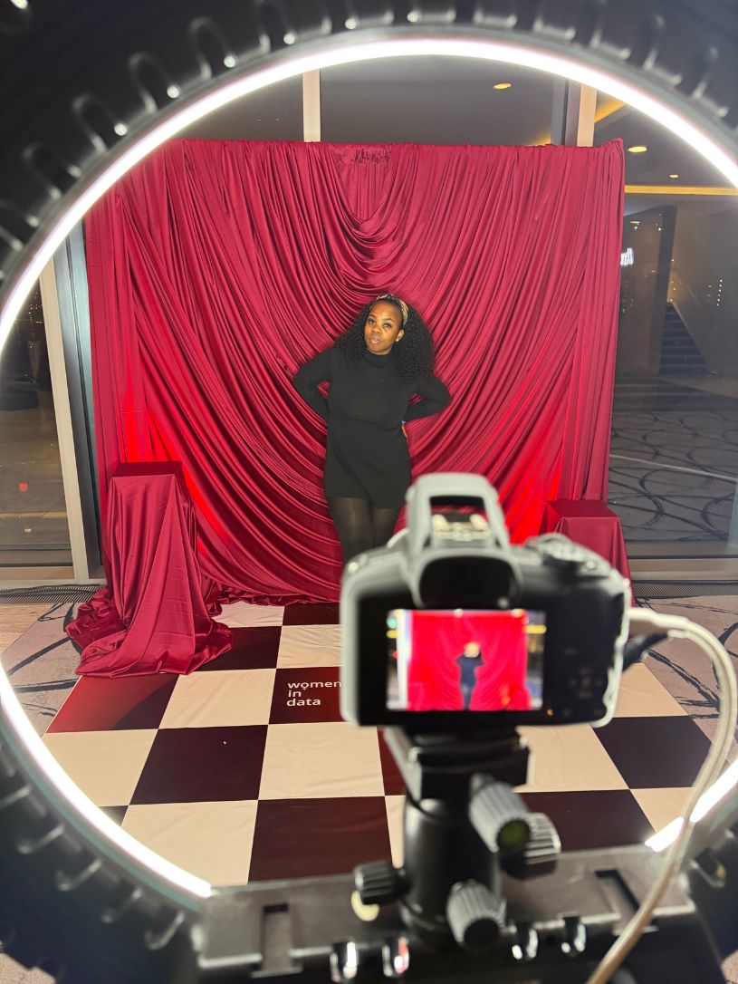 Guest posing at the HD Glam Studio Experience photo booth with a red draped backdrop, ring light and professional DSLR camera at a Women in Data corporate event in London