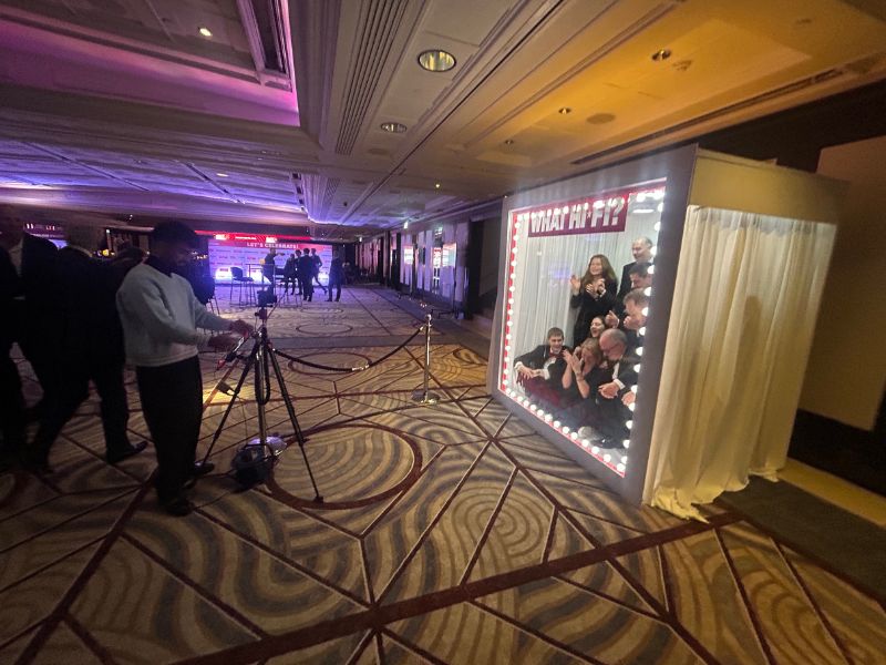 Guests gathering around a lit magazine photo booth watching a group shoot